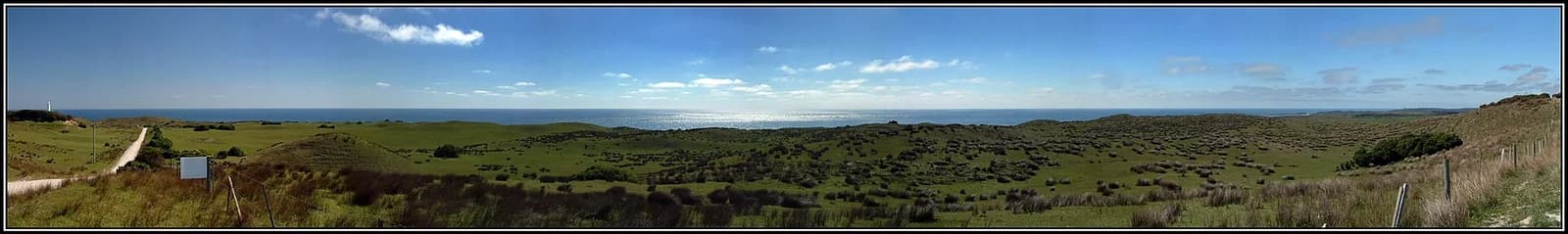 The coast and lighthouse at Cape Wickham; representative setting, not a photograph of the named golf course
