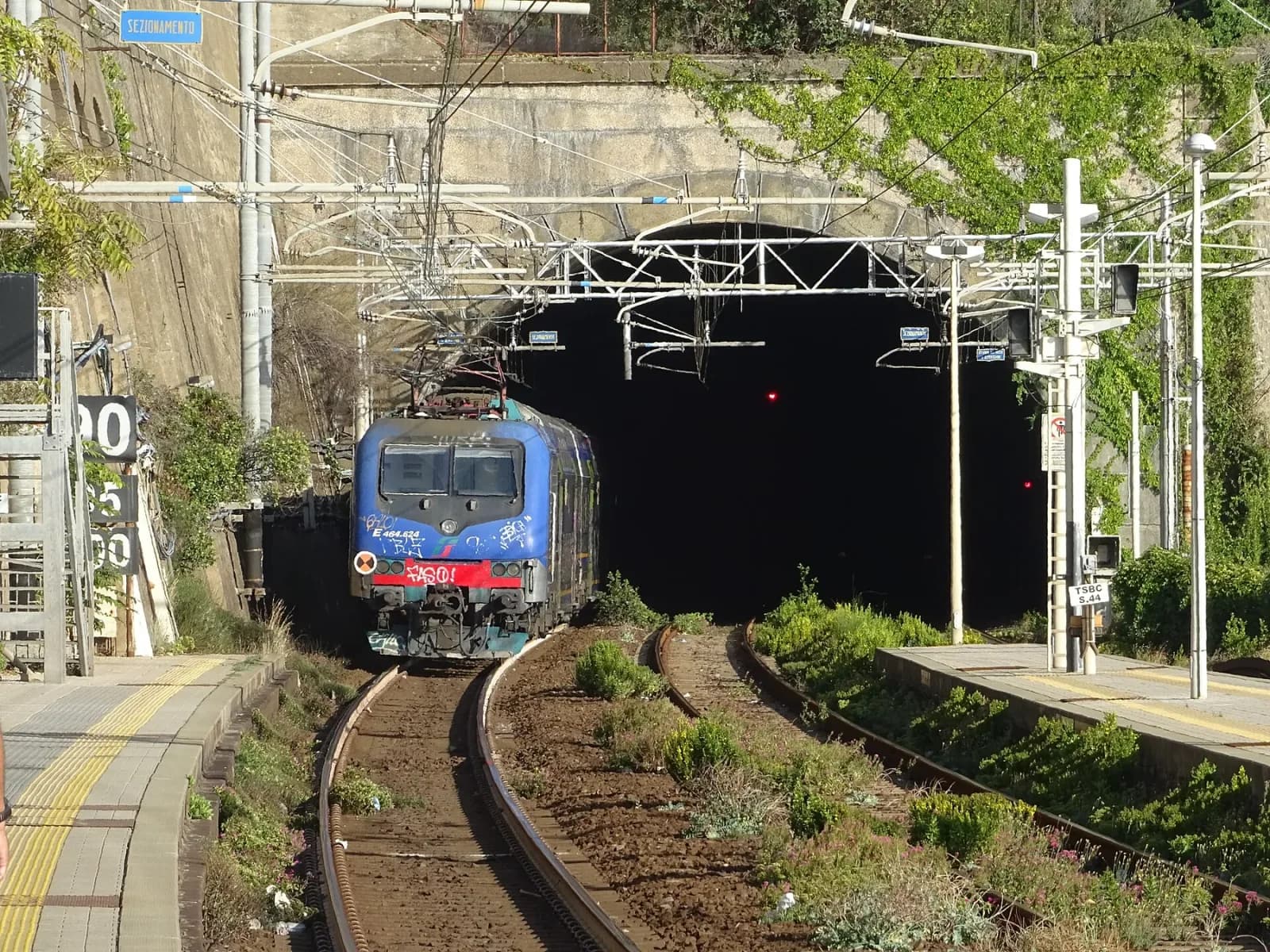 A Cinque Terre regional train emerging from a tunnel beside Corniglia station