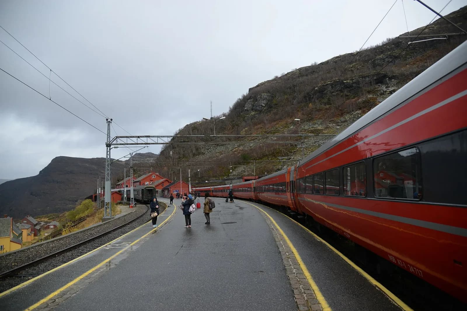 Red Flåm Railway carriages waiting between steep dark mountains at Myrdal
