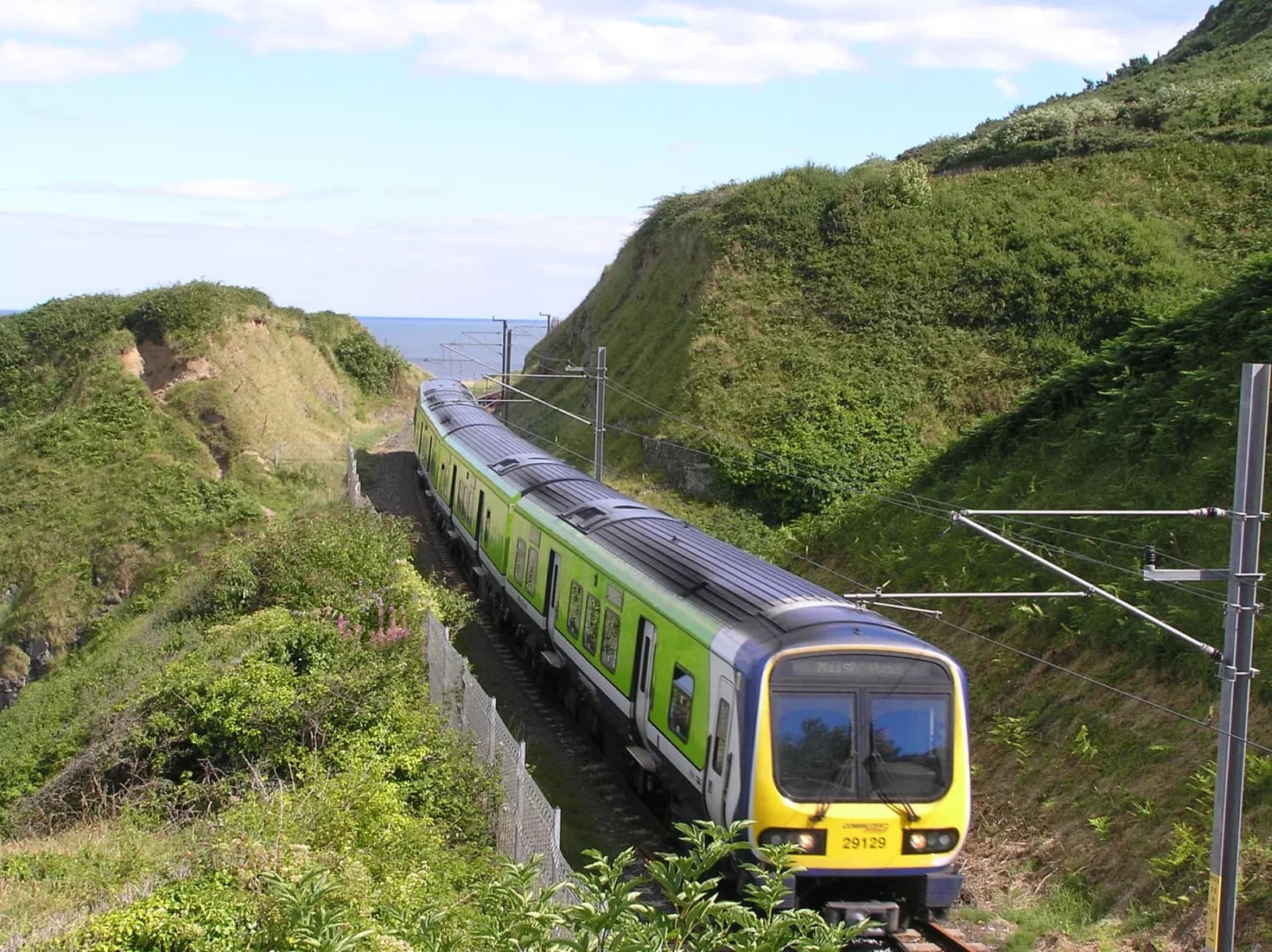 An Irish InterCity train curving around the coastal railway beneath Bray Head